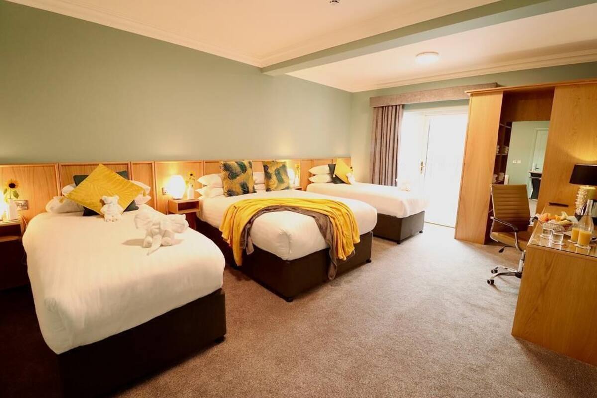 A hotel room with two beds, a desk, and a wardrobe.