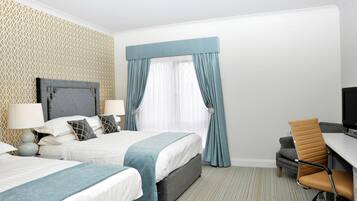 A hotel room with two beds, a desk, a chair, and a television.