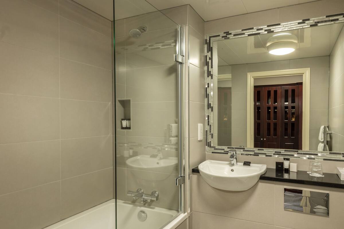 A modern bathroom with a glass-enclosed shower, a white sink, and a toilet.