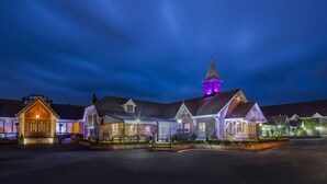 A historic building with a prominent clock tower, large windows, and a well-lit entrance. - Treacys Oakwood Hotel (Shannon)