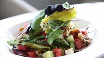 Ensalada con diversos vegetales y una hoja de lechuga sobre un plato blanco.