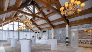 A spacious hall with high wooden beams, a chandelier, and a patterned carpet. Tables and chairs are arranged for events. - Treacys Oakwood Hotel (Shannon)