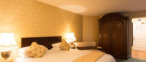Une chambre d’hôtel avec un grand lit, deux lampes de chevet, une armoire en bois et une porte avec une serrure.