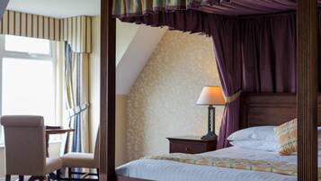 A bedroom with a four-poster bed, a desk, and a chair.