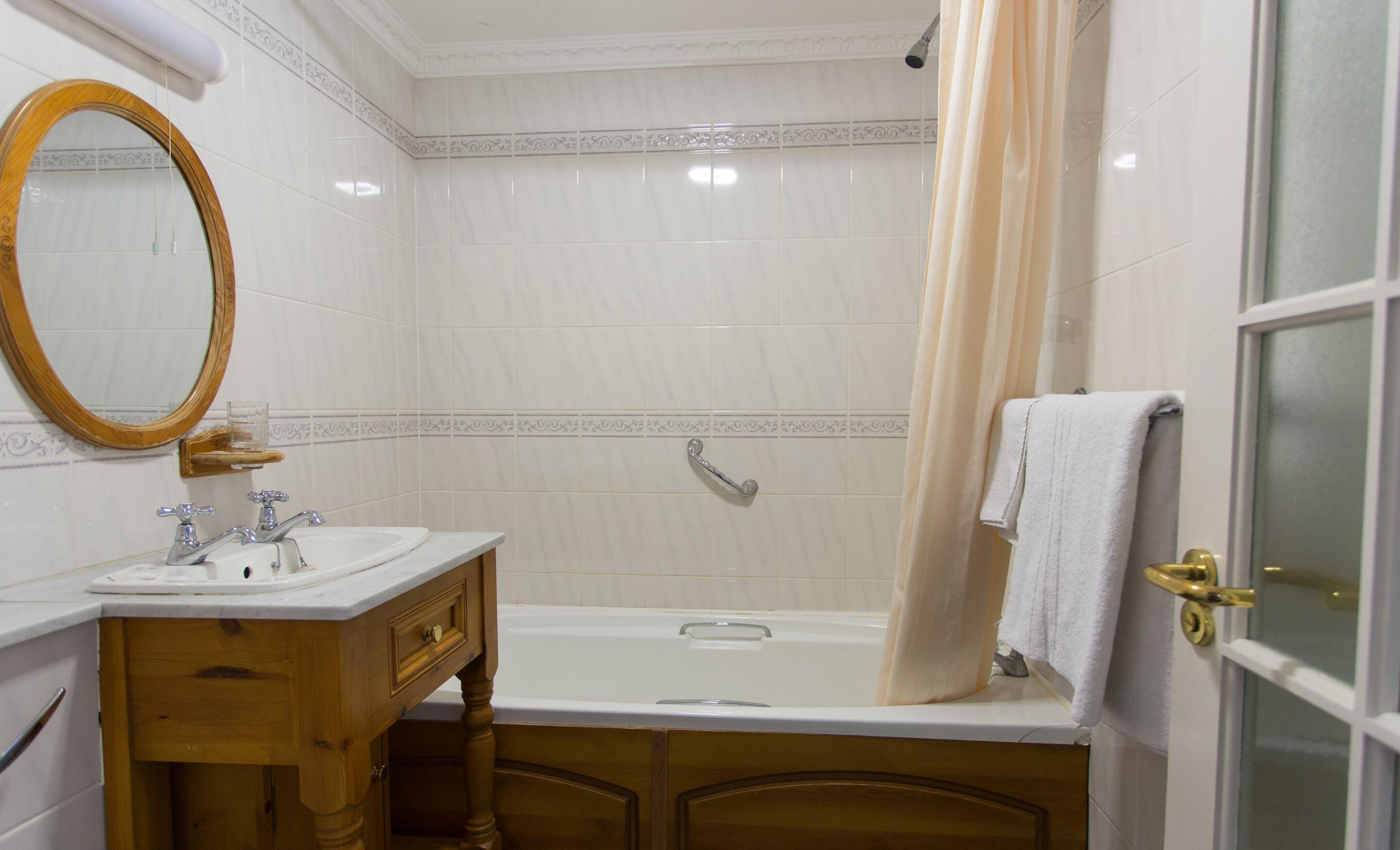 Un baño con tocador de madera, bañera, cortina de ducha y espejo.