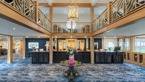 A spacious lobby with a central round table, a reception desk, and a staircase connecting two floors. - Connemara Coast Hotel (Galway)