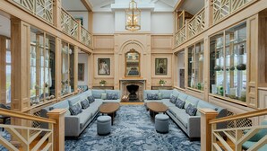 A grand room with a central fireplace, two sofas facing each other, and a chandelier. - Connemara Coast Hotel (Galway)