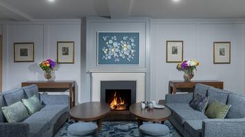 A modern living room with a fireplace, two sofas, a coffee table, and framed artwork on the walls.
