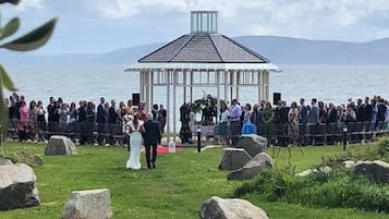 A gazebo with a clear view of the sea and mountains in the background.