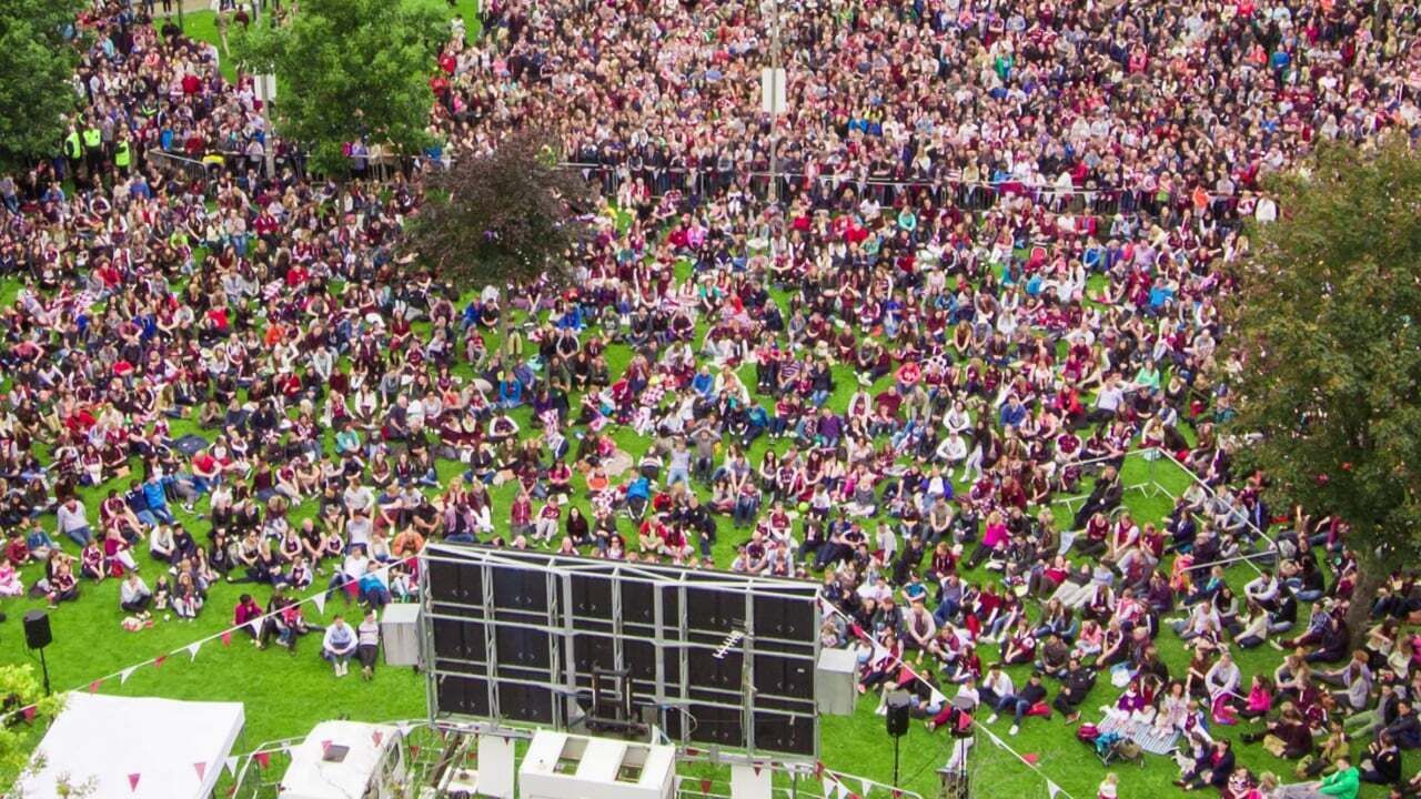 Un grand rassemblement en plein air avec une scène et un espace réservé aux spectateurs.