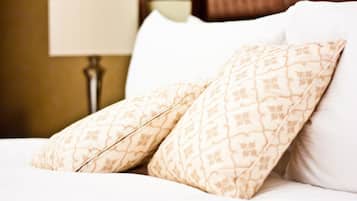 A bed with two patterned pillows and a lamp in the background.