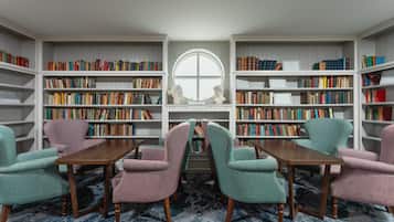 Een bibliotheek met boekenkasten, een rond raam en een tafel met stoelen.