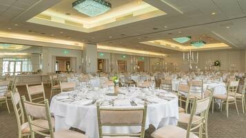Un salón de banquetes con mesas redondas dispuestas para comer, equipado con sillas y vajilla.