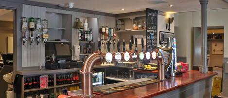 A bar area with multiple beer taps and shelves stocked with bottles.