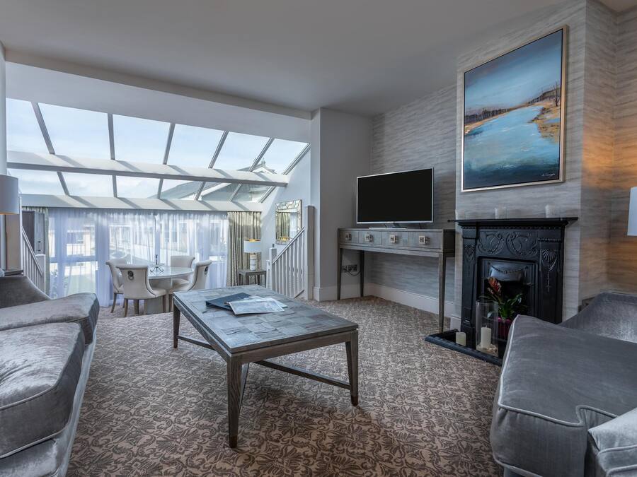 A modern living room with a fireplace, a large painting, and a view through a skylight.