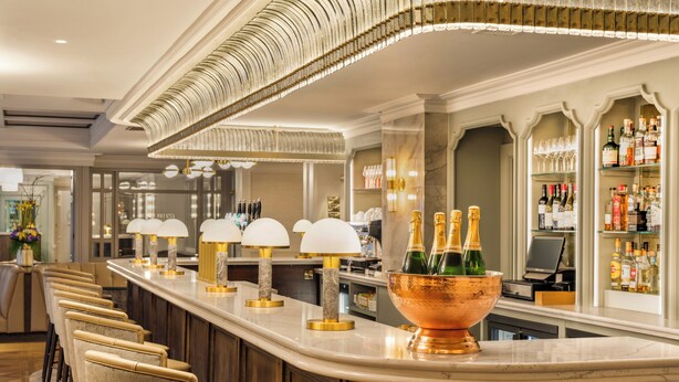 A bar area with a long counter, cushioned bar stools, and a copper bowl with champagne bottles. - Brooks Hotel (Dublin)