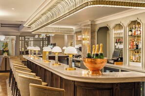 A bar area with a long counter, cushioned bar stools, and a copper bowl with champagne bottles. - Brooks Hotel (Dublin)