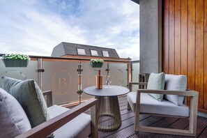 A modern outdoor seating area with a round table, cushioned chairs, and a wooden wall. - Brooks Hotel (Dublin)