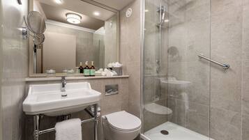 A modern bathroom with a glass-enclosed shower, a white sink, and a toilet.