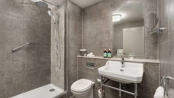 Un baño moderno con ducha, inodoro, lavabo y espejo.