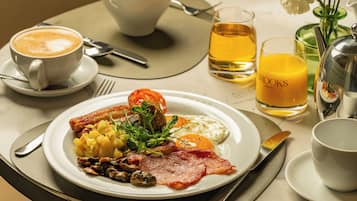 A breakfast setting with a plate of food, a cup of coffee, a glass of orange juice, and a bottle of water.