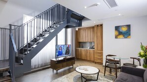Una sala moderna con una escalera, una zona de cocina y un comedor.