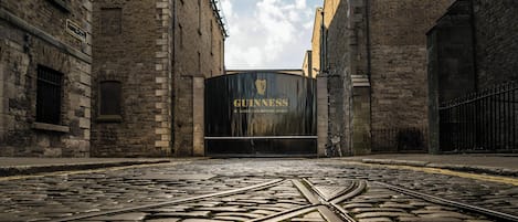 Een geplaveid pad dat leidt naar een groot zwart hek met het Guinness logo.