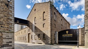 A historic building with a stone facade, a sign for Guinness St. James's Gate Brewery, and a cobblestone street.