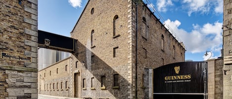 Un edificio histórico con fachada de piedra, un cartel de Guinness St. James's Gate Brewery y una calle adoquinada.