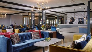 A modern hotel lobby with a blue sofa, yellow armchairs, a reception desk, and a chandelier. - Camden Court Hotel (Dublin)