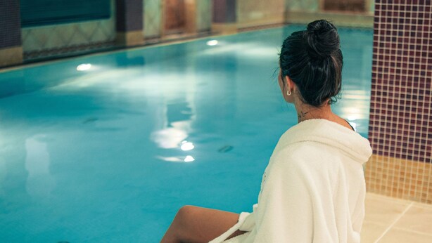 A person sitting by a pool with a tiled wall in the background. - Camden Court Hotel (Dublin)