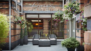 The exterior of Camden Court Hotel with a brick facade, hanging flower baskets, and outdoor seating area with wicker chairs and tables. - Camden Court Hotel (Dublin)