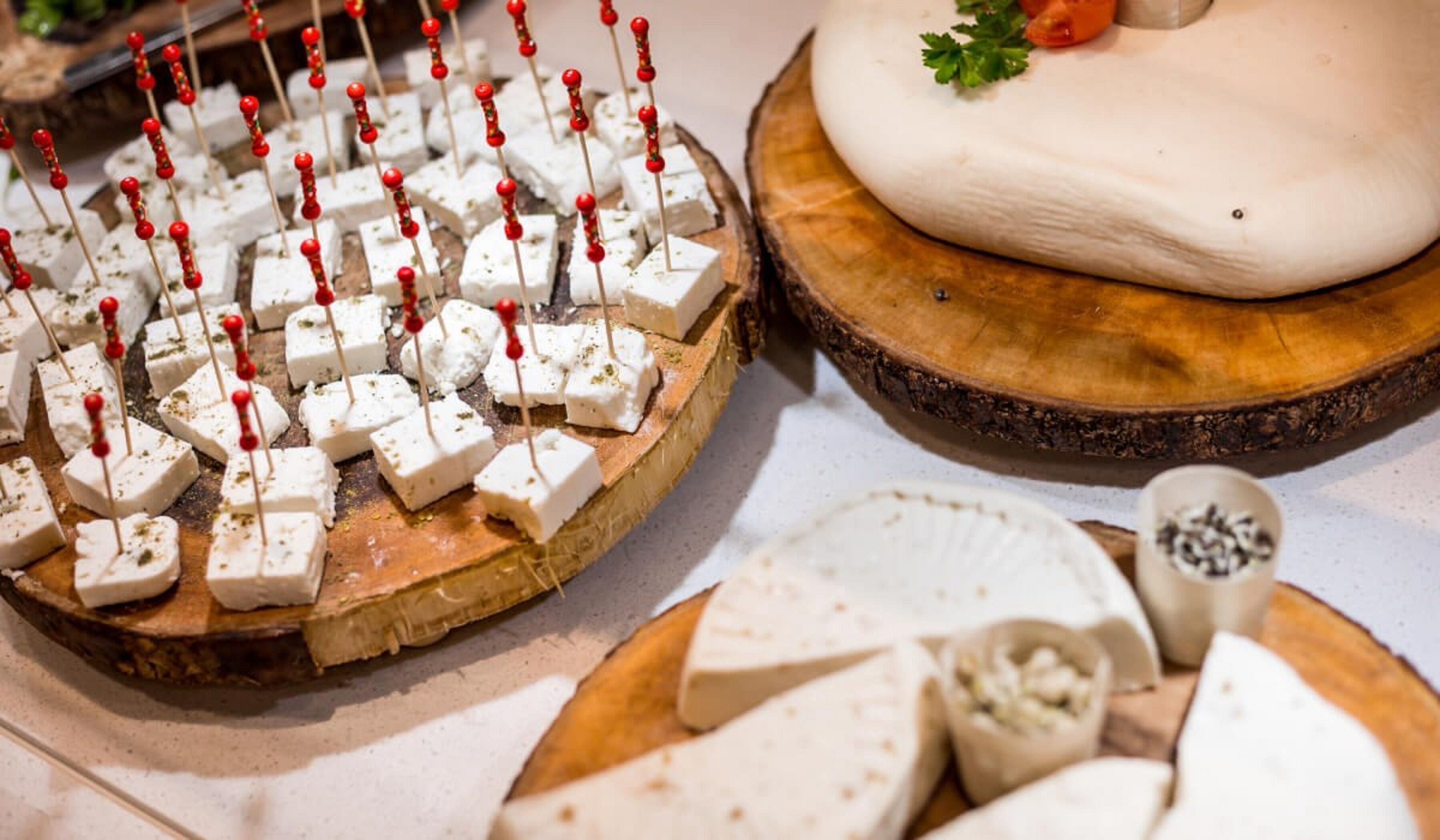 A cheese board with various types of cheese, some with skewers, and a wooden serving board.