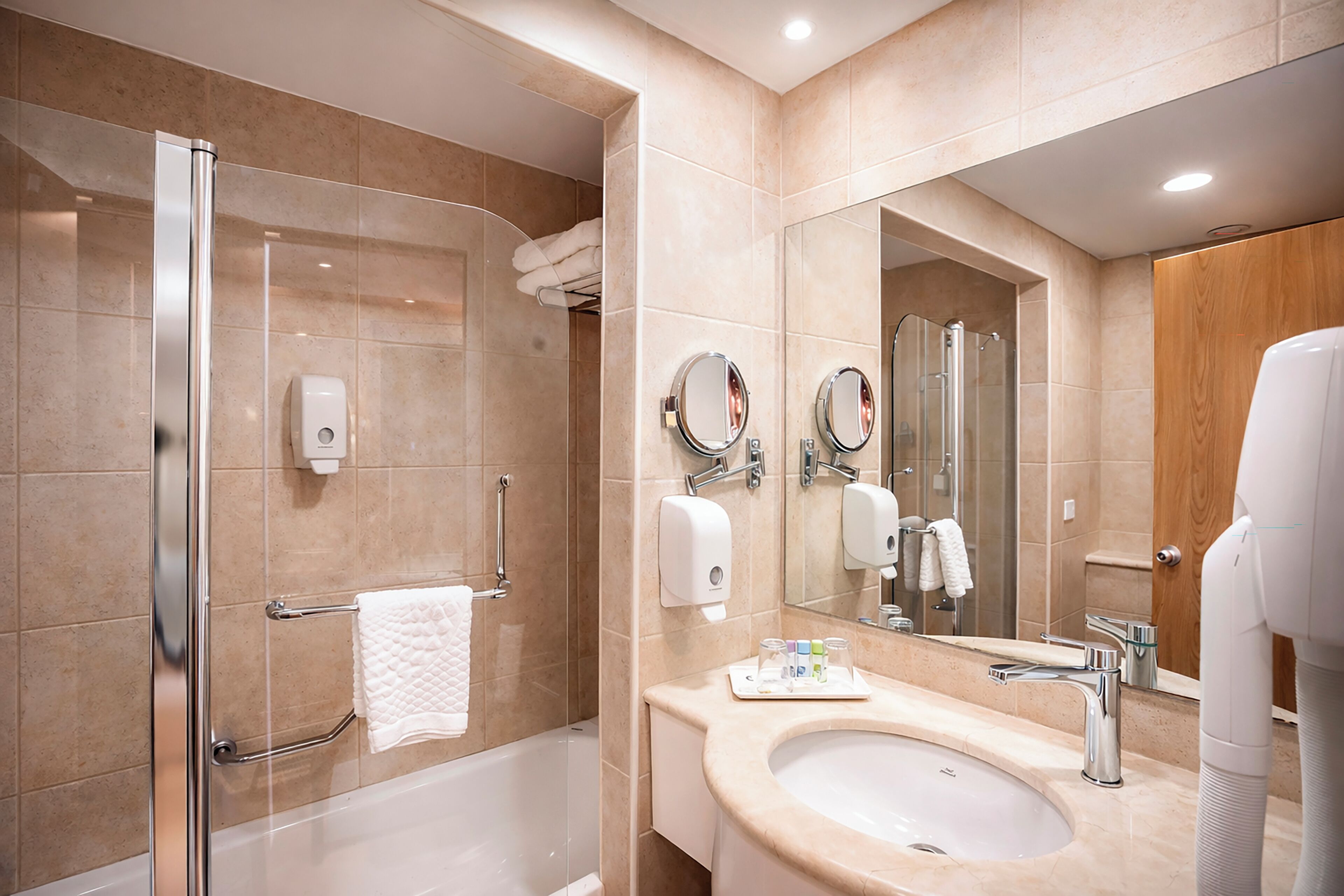 A modern bathroom with a glass-enclosed shower, a sink with a vanity, and a large mirror.