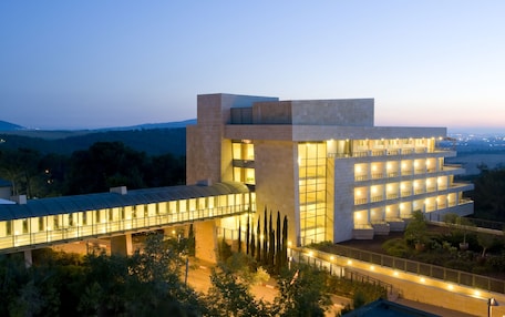 A modern hotel with a glass facade, multiple balconies, and a covered walkway.