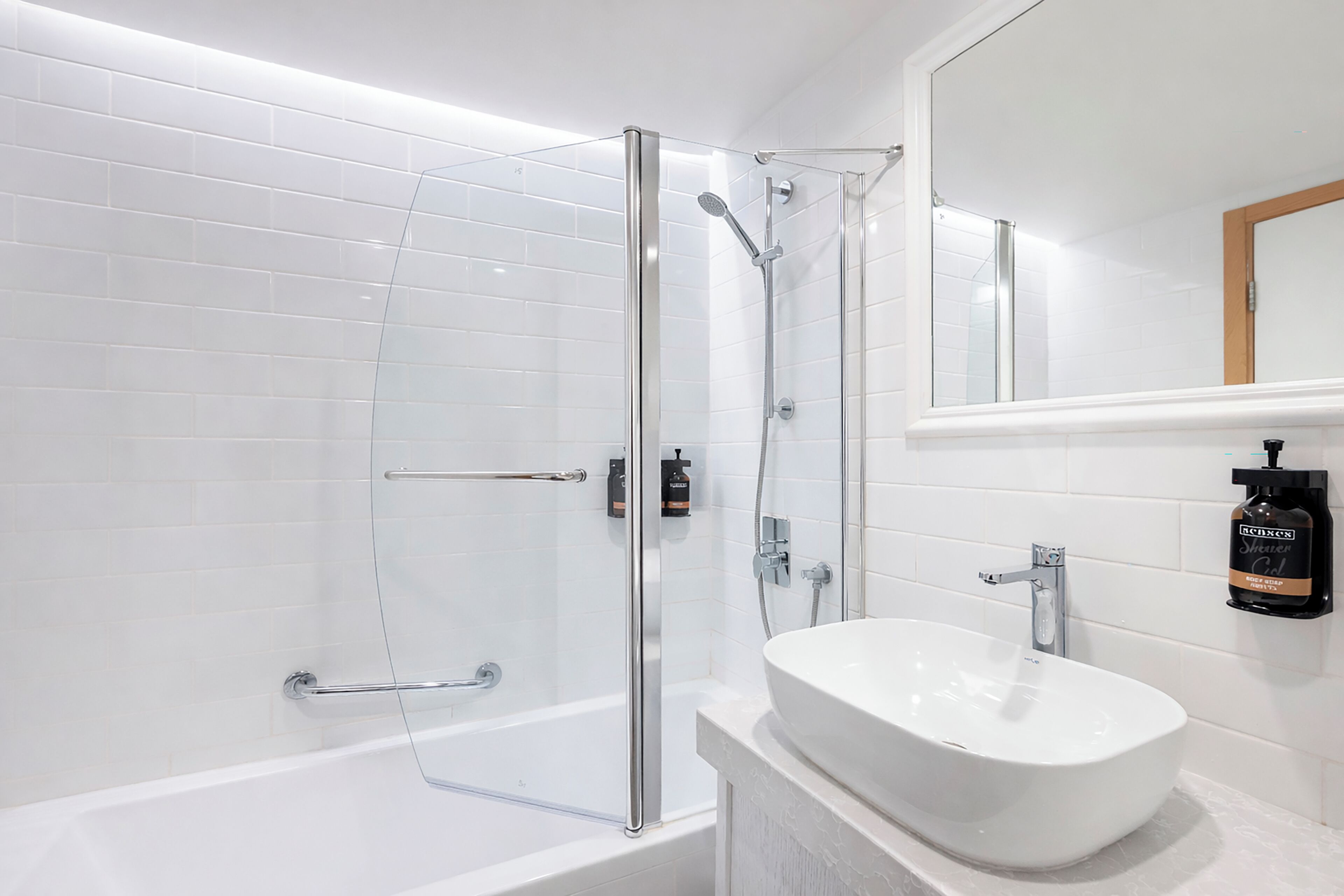 A modern bathroom with a glass shower enclosure, a white bathtub, and a white sink with a mirror above.
