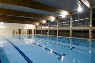 Una piscina interior con carriles delimitados, ventanas amplias y un techo alto.