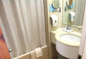 Un baño con cortina de ducha, lavabo, espejo y dispensador de jabón.