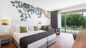 Ett hotellrum med en säng, en soffa, ett litet bord och en balkong med utemöbler.