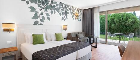 Habitación de hotel con cama, sofá, una pequeña mesa y balcón con mobiliario exterior.
