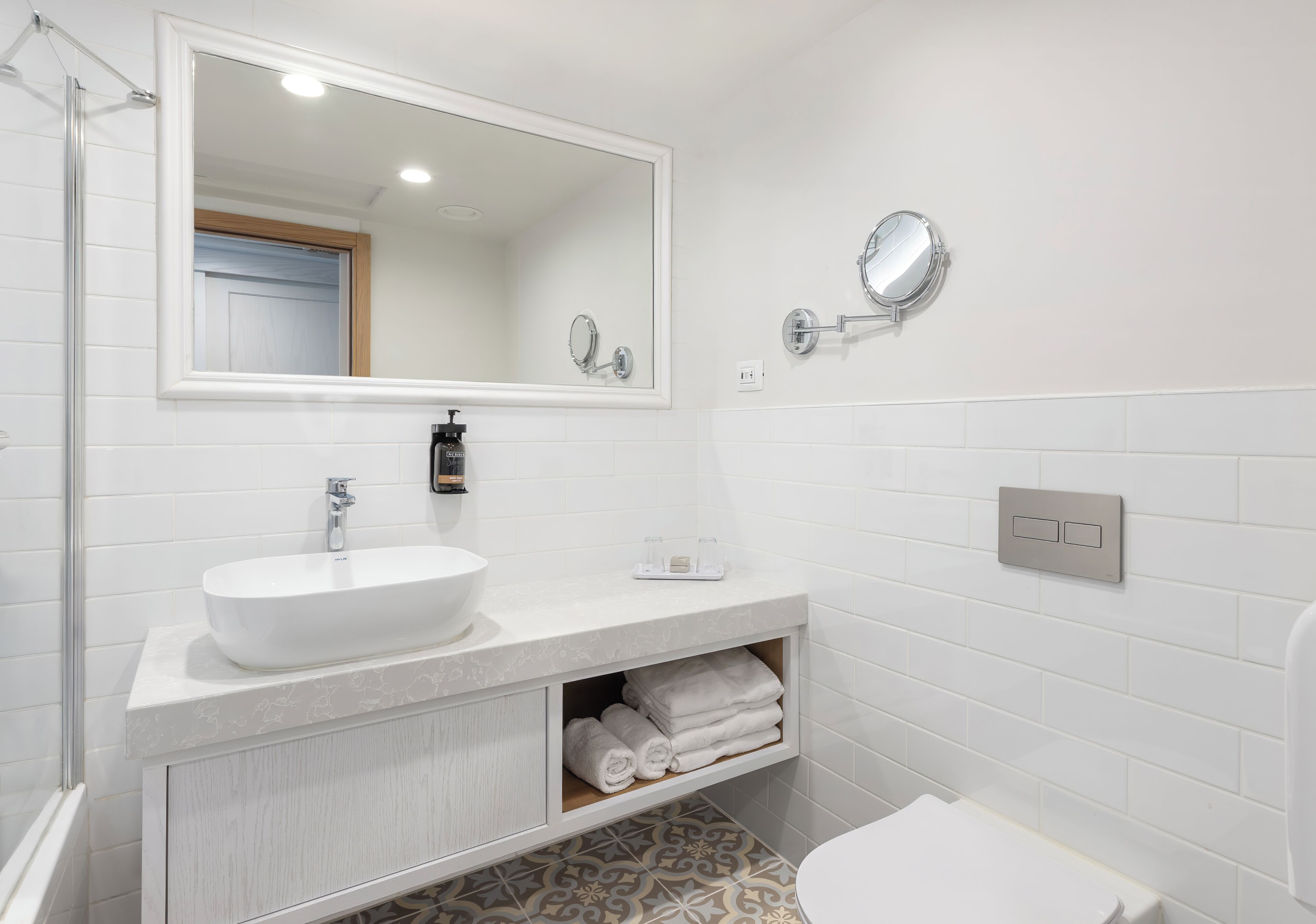 A bathroom with a white sink, a large mirror, a shower, and a toilet.