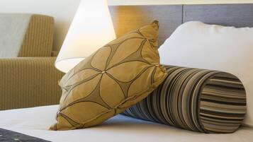 A bed with a patterned pillow and a striped pillow, a lamp, and a headboard.