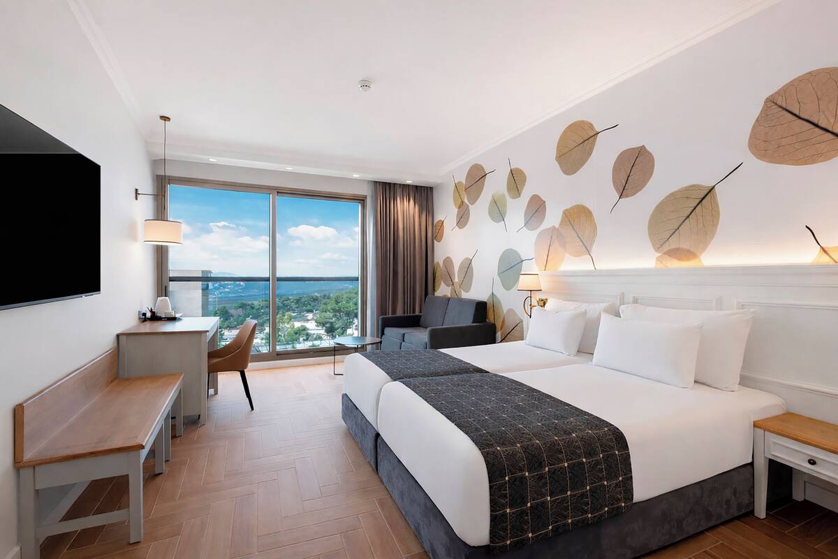Ein Hotelzimmer mit einem großen Bett, einem Schreibtisch, einem Sessel und einem Fernseher.