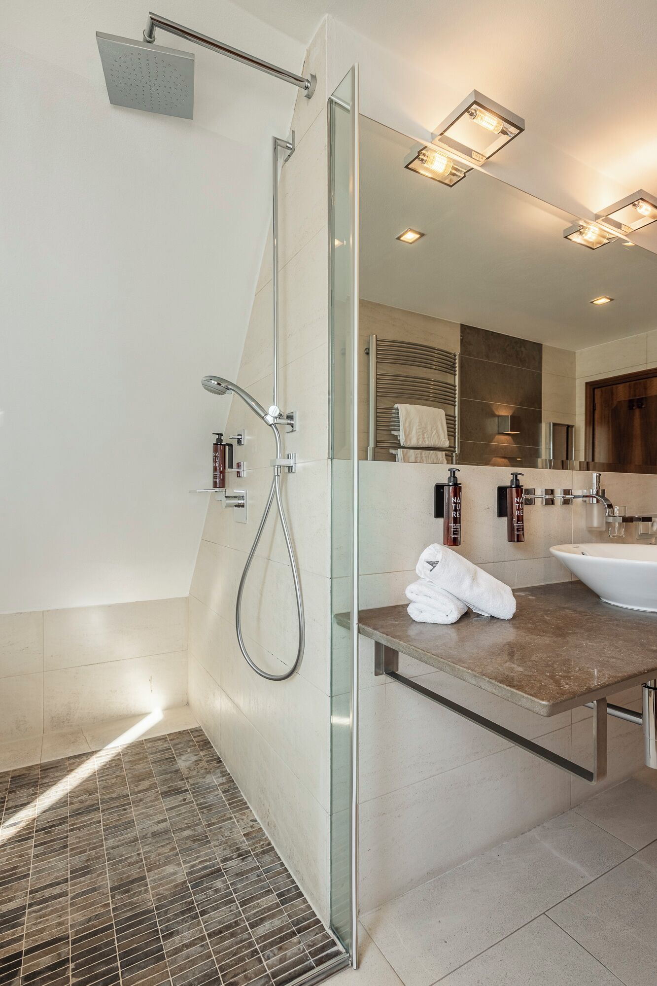 Un baño moderno con cabina de ducha de vidrio, tocador con lavabo y un perchero para toallas.