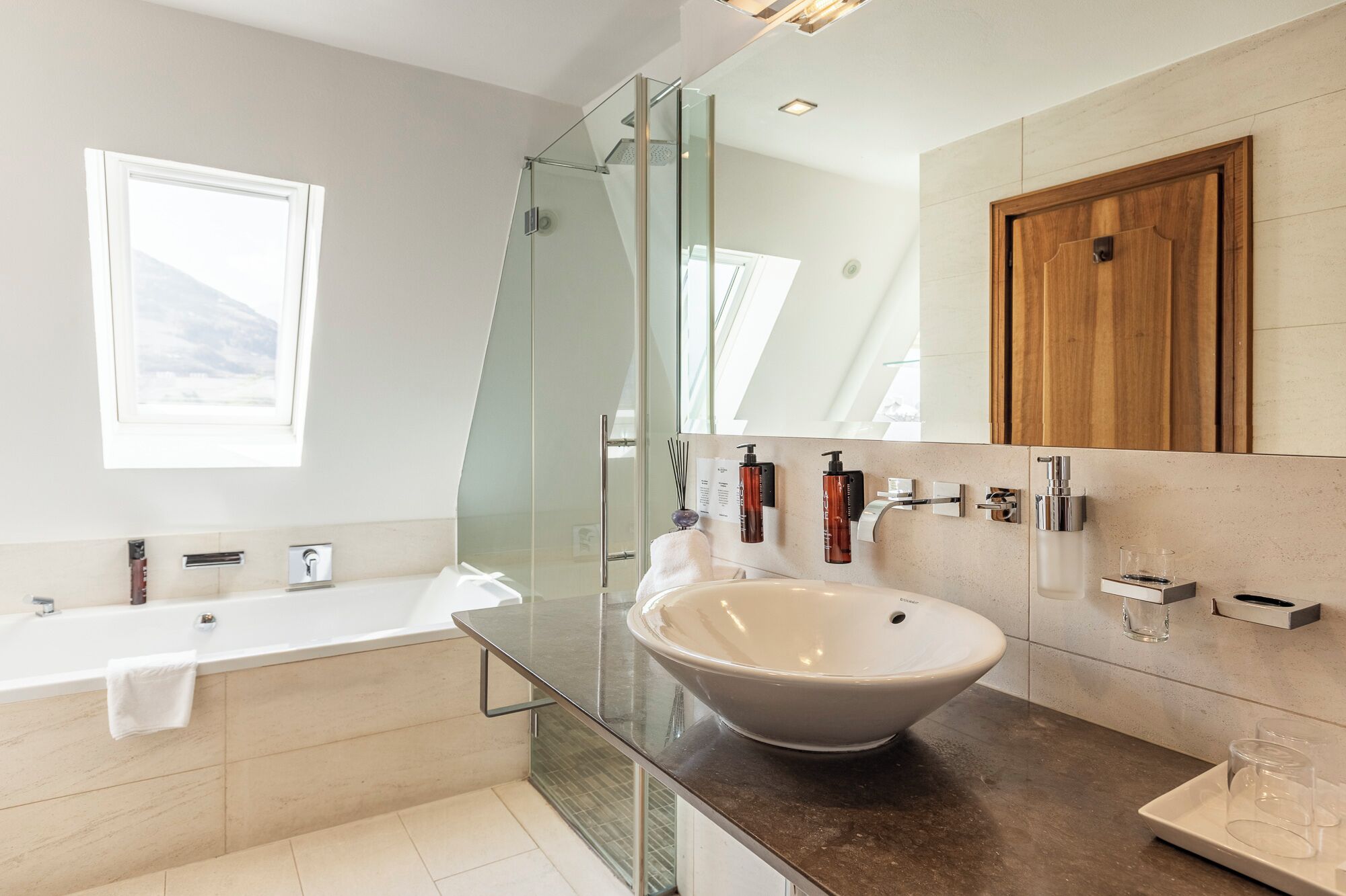 Une salle de bain moderne avec une douche à parois de verre, un grand lavabo sur pied et une porte en bois.