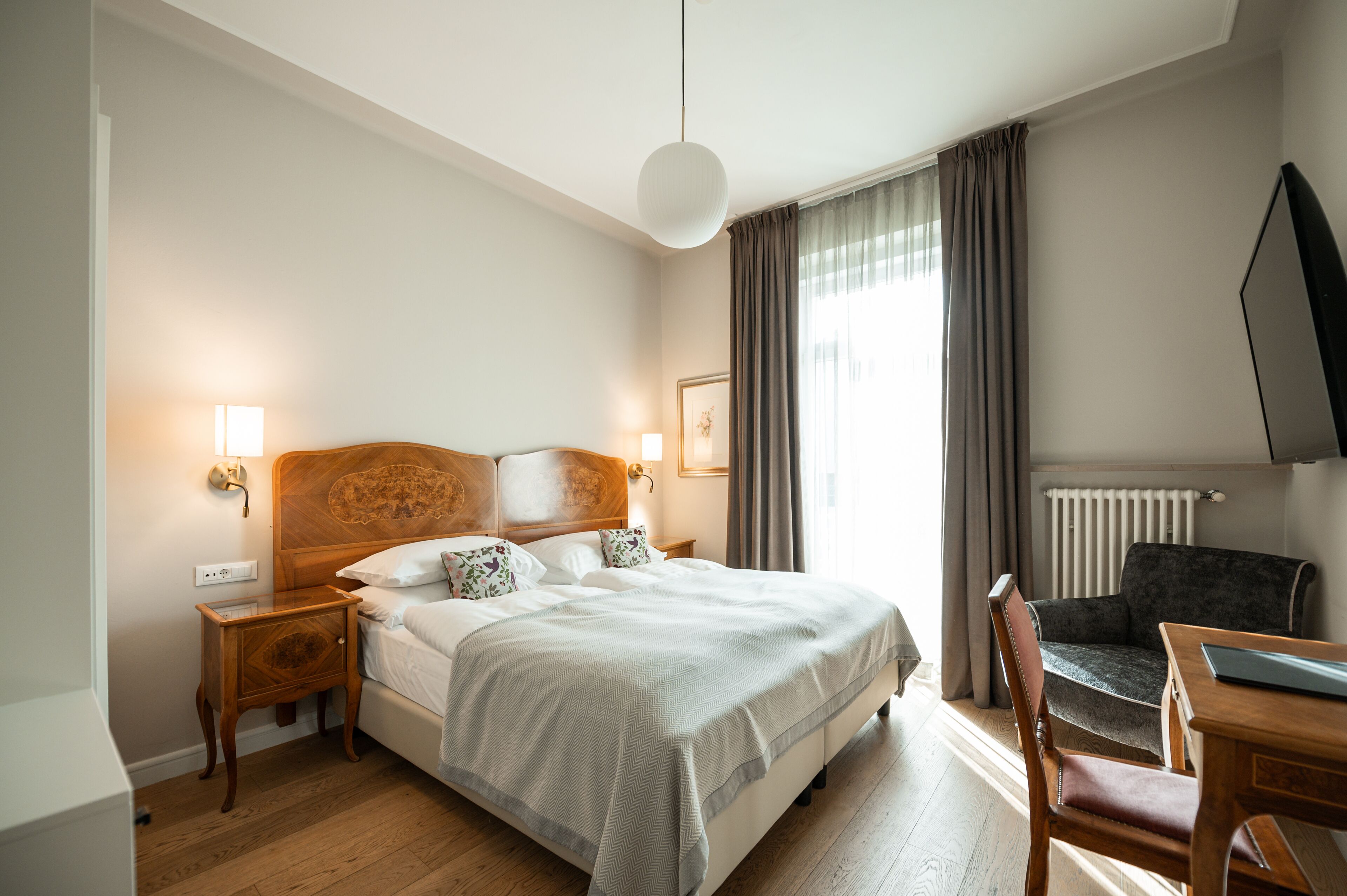 Una habitación de hotel con una cama grande, mesitas de noche, un escritorio y una silla.