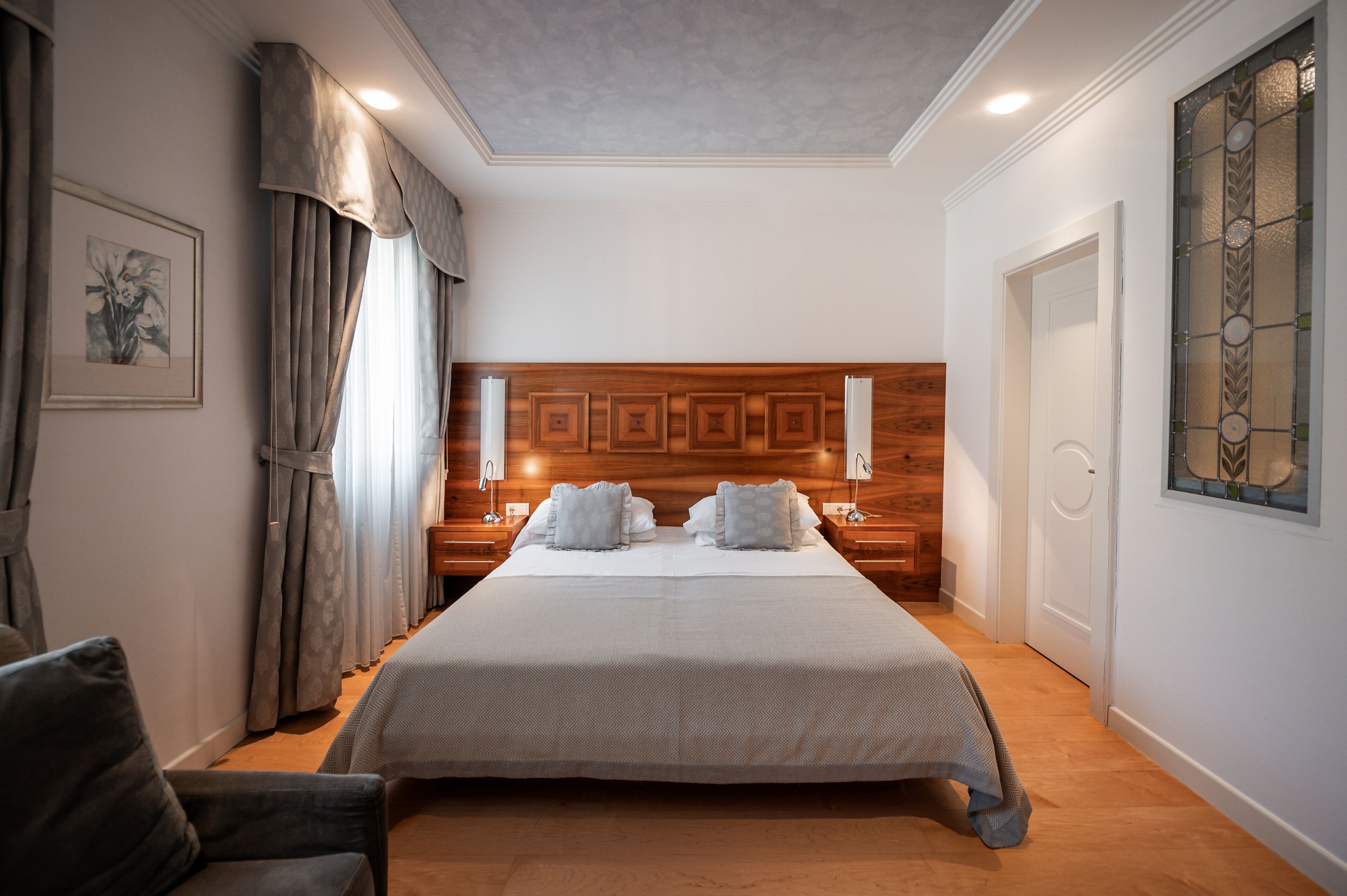 A neatly arranged bedroom with a large bed, wooden headboard, bedside tables, and a framed picture on the wall.