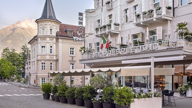 Un hôtel doté d’un balcon, de plantes en pot et de drapeaux.