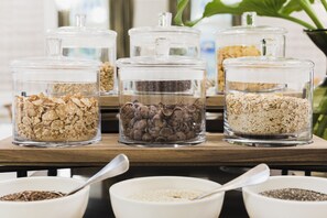 Four glass jars with lids containing different types of grains and seeds on a wooden table. - Hotel Europa Splendid (Merano)