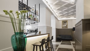 Une cuisine moderne avec un coin bar, une table à manger avec des chaises et un grand vase rempli de fleurs.